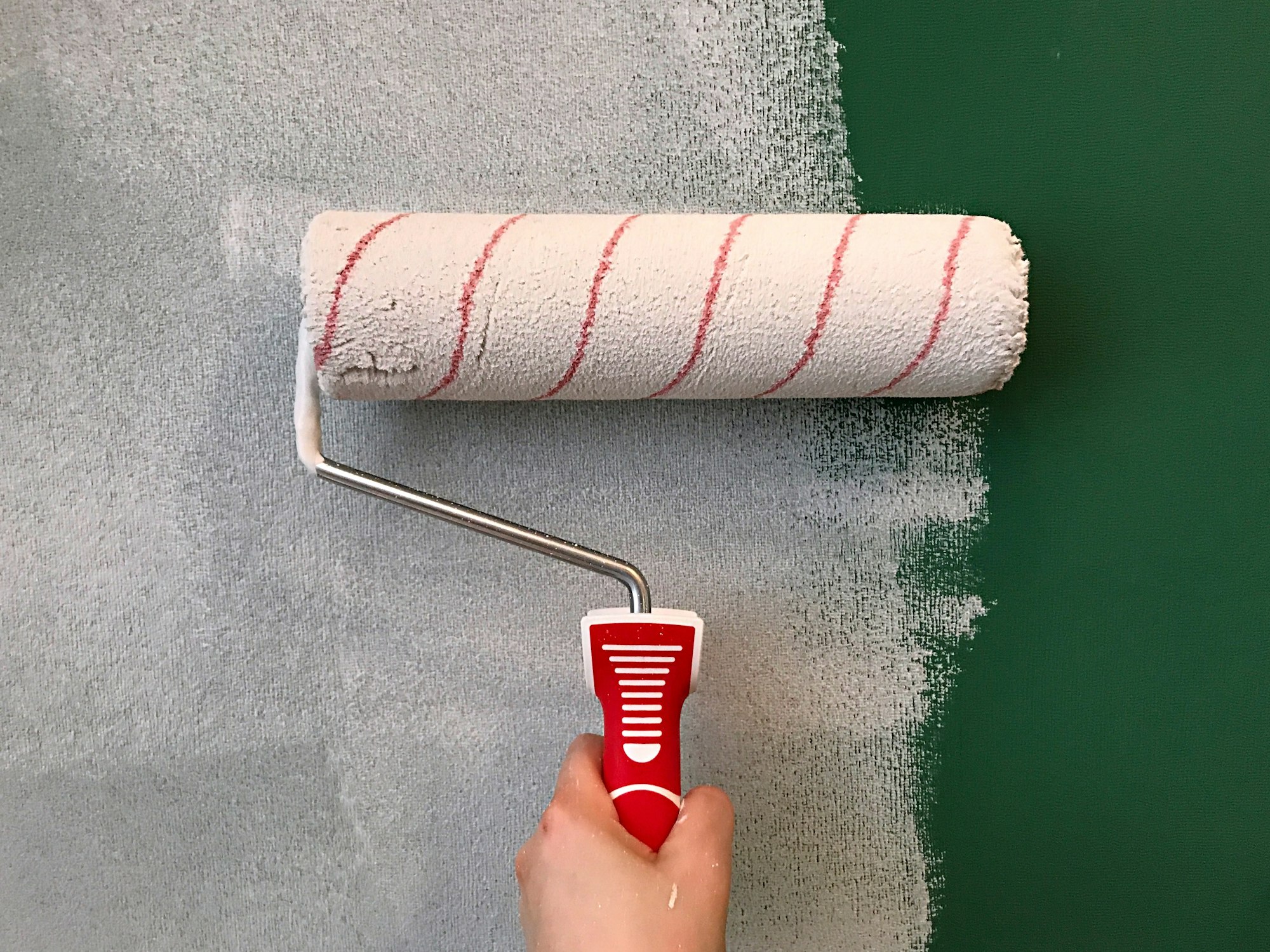 Woman painting a green wall with paint roller